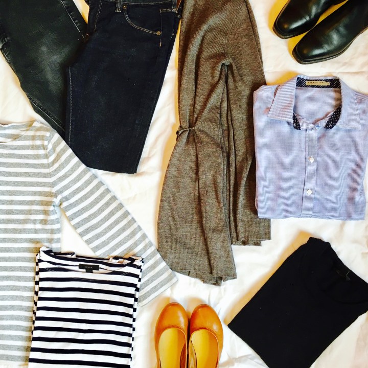Flat lay of long weekend capsule wardrobe focused on stripes and black, grey and blue.