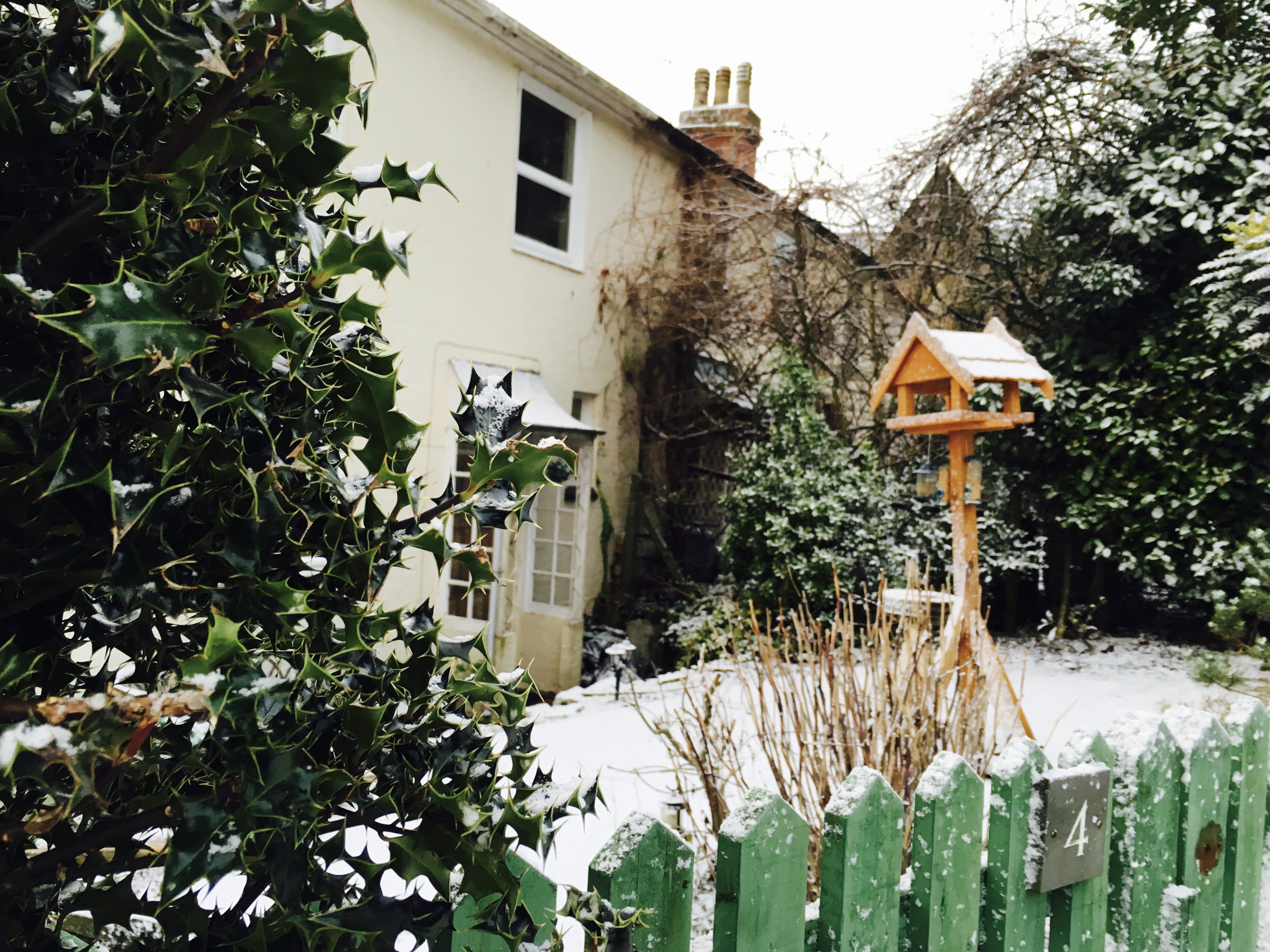 Snow covered front yard of Georgian house with bird feeder 