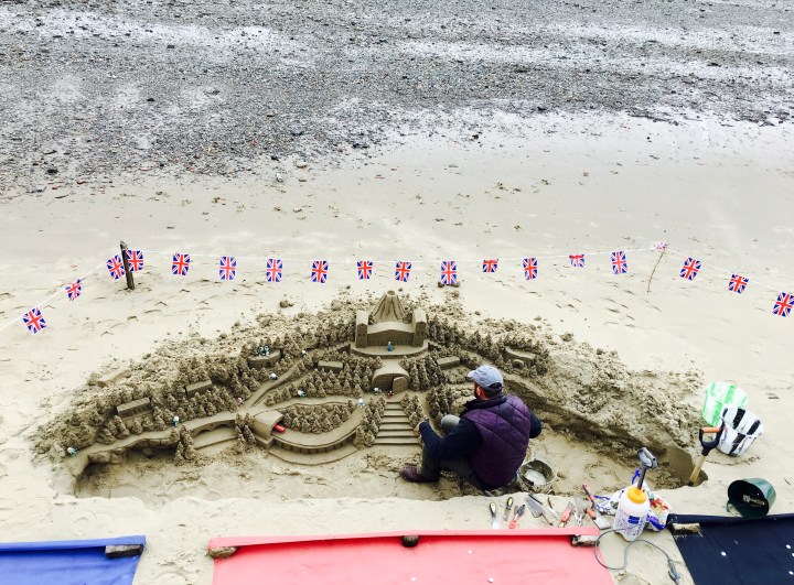 Man building a sandcastle on the banks of the Thames River, London.
