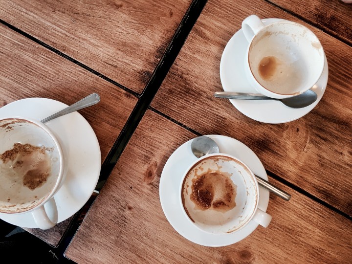 Empty coffee cups sitting on a wooden table.