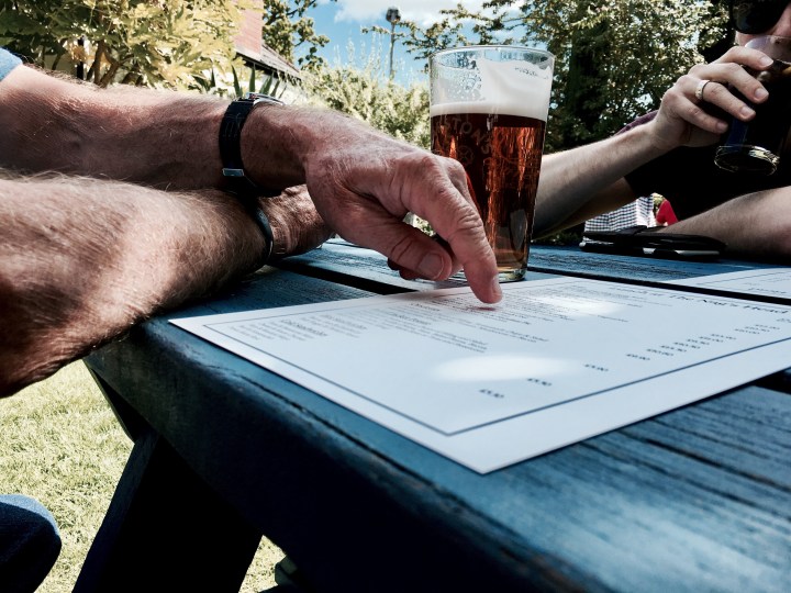 Hand pointing at a menu at a beer garden in rural England.