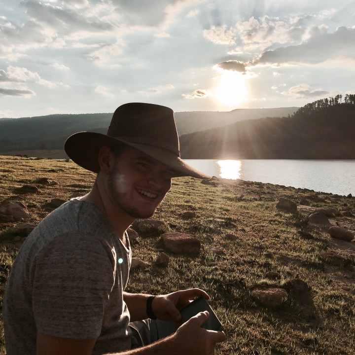 Man in Akubra hat watching sunset over a body of water.