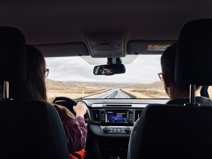 Man and woman in car driving in Iceland.