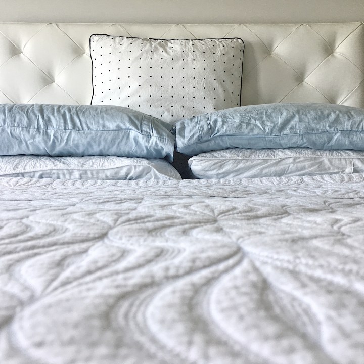 Bed made up with black, white and light blue table linens.
