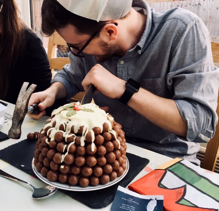 A chocolate Christmas pudding being cut with a knife and hammer.