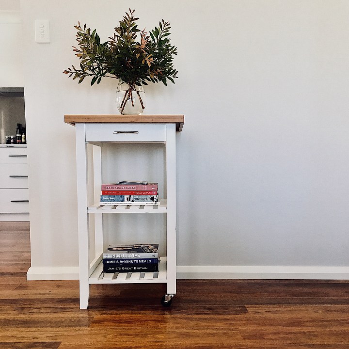 Vase of Australian native greenery sitting on a white and bamboo kitchen caddy.