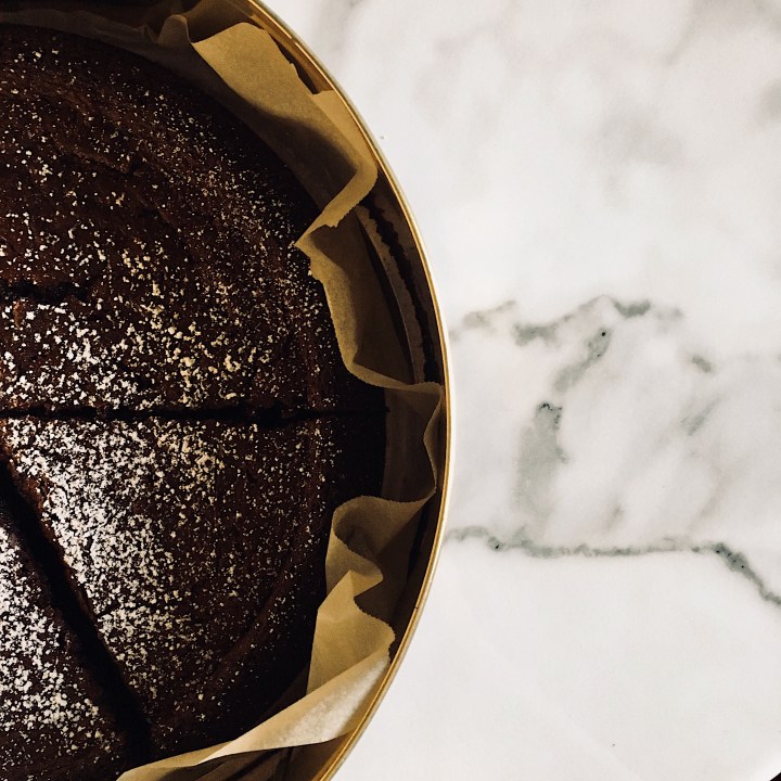 Nigella Lawson's chocolate olive oil cake sitting in a cake tin.