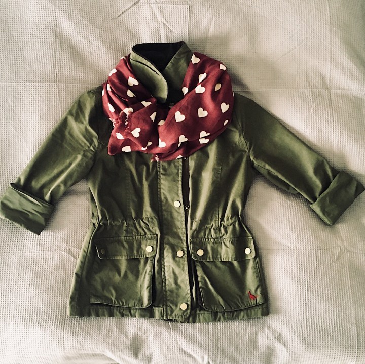 Flat lay of olive cotton jacket and burgundy scarf.