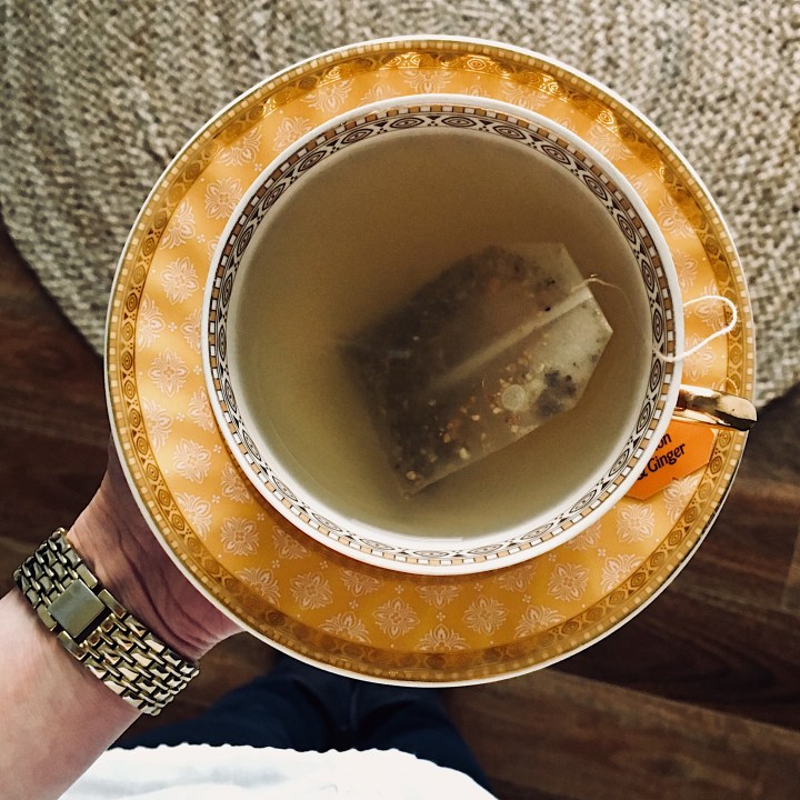 Hand holding cup of tea.