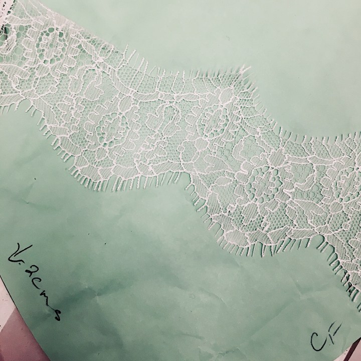 French lace sitting on top of a paper dress pattern.
