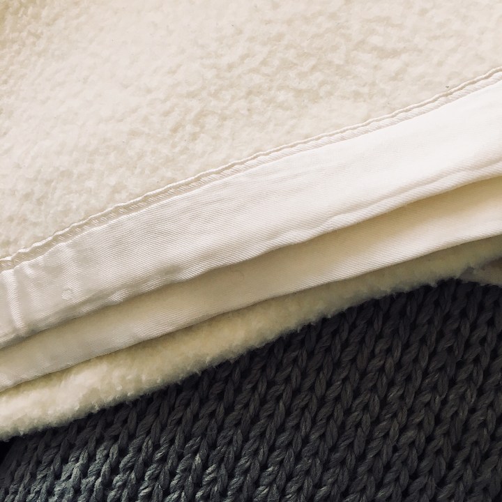 White blanket and grey knit pillow.