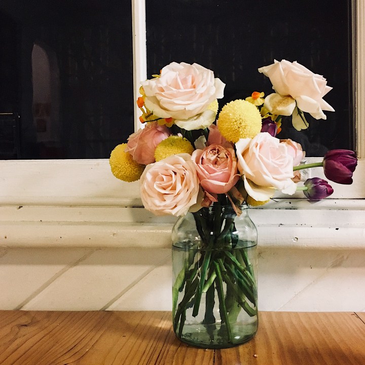 A bunch of flowers sitting on a table by a window.