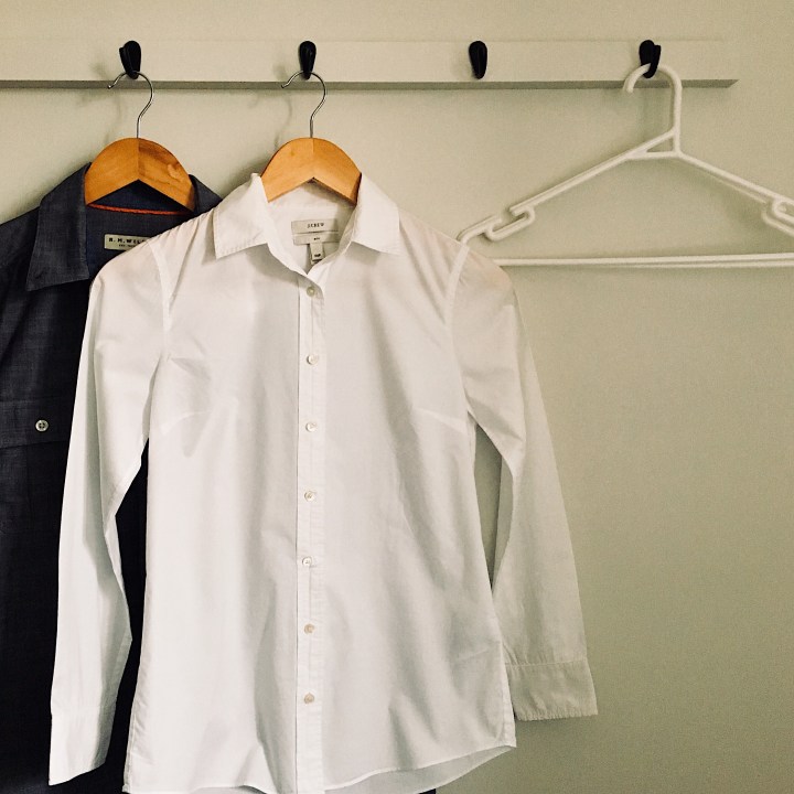 Shirts and coat hangers on a coat rack.