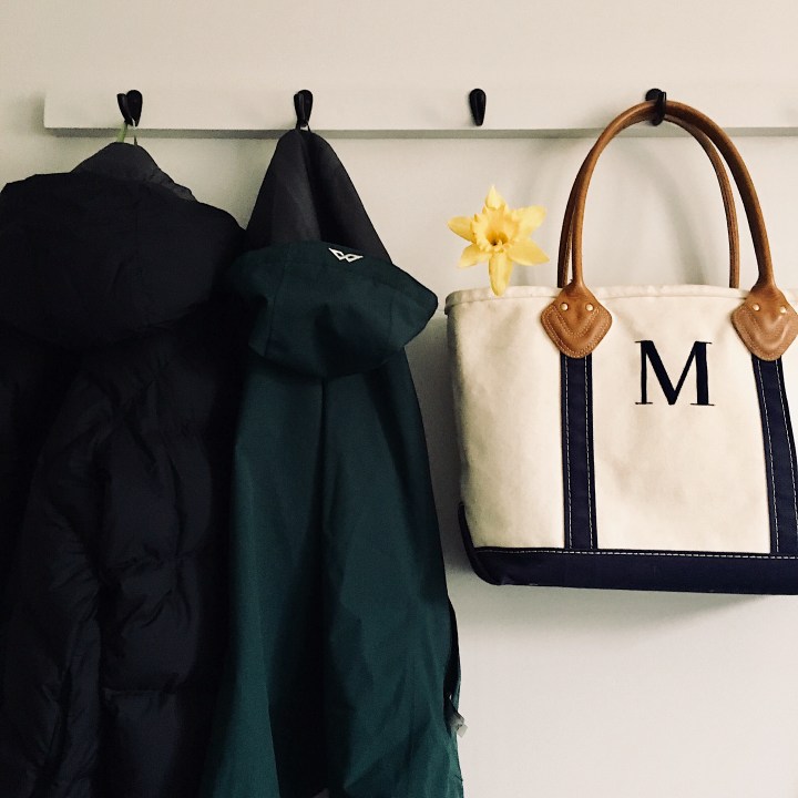 Coats and a canvas bag hanging on a coat rack.