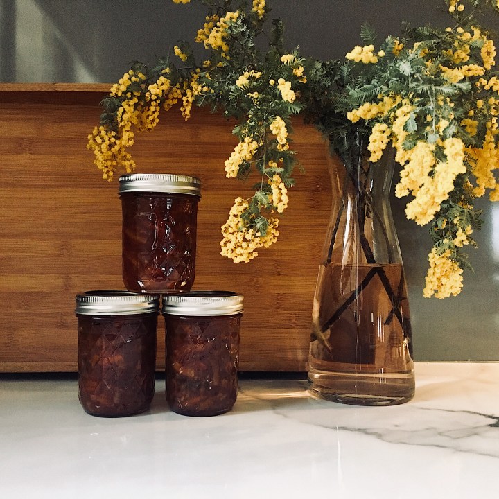 Jars of marmalade beside a vase of Australian wattle.