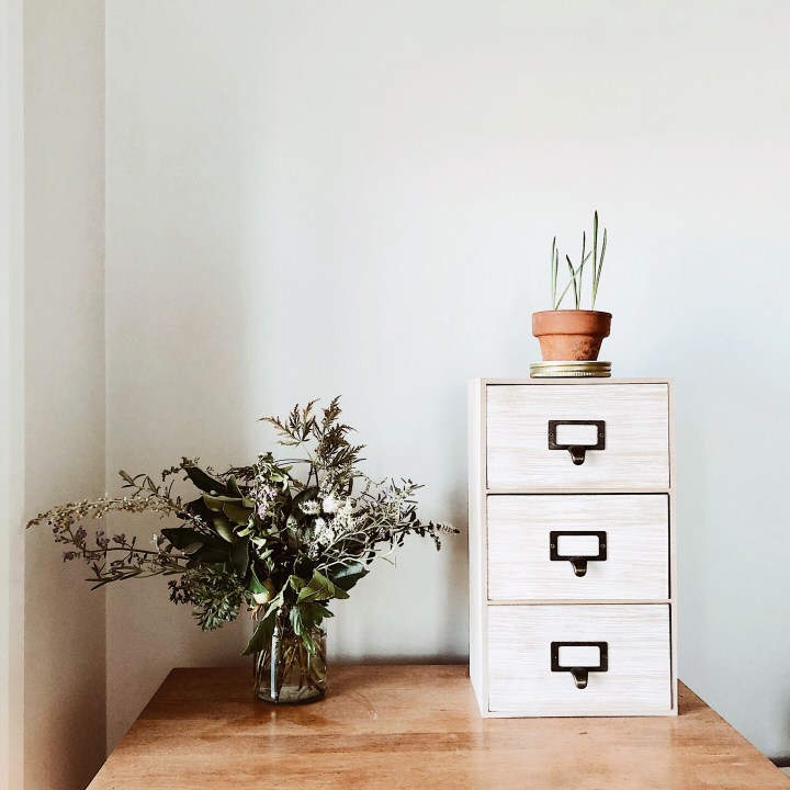 Bouquet garni in jar beside set of draws, with small terracotta pot sitting on top.