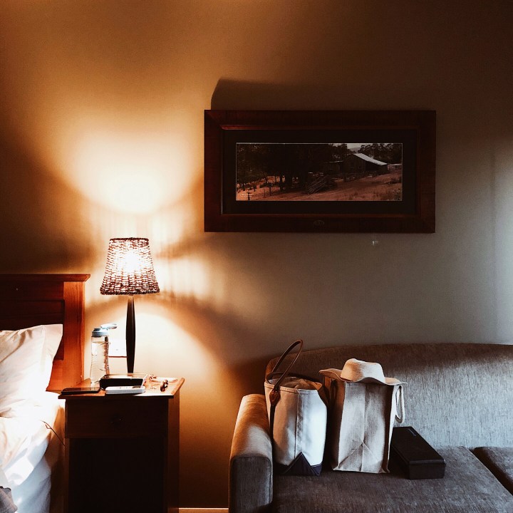 A bed, bedside table and lounge chair of a hotel in Hay, New South Wales, Australia.
