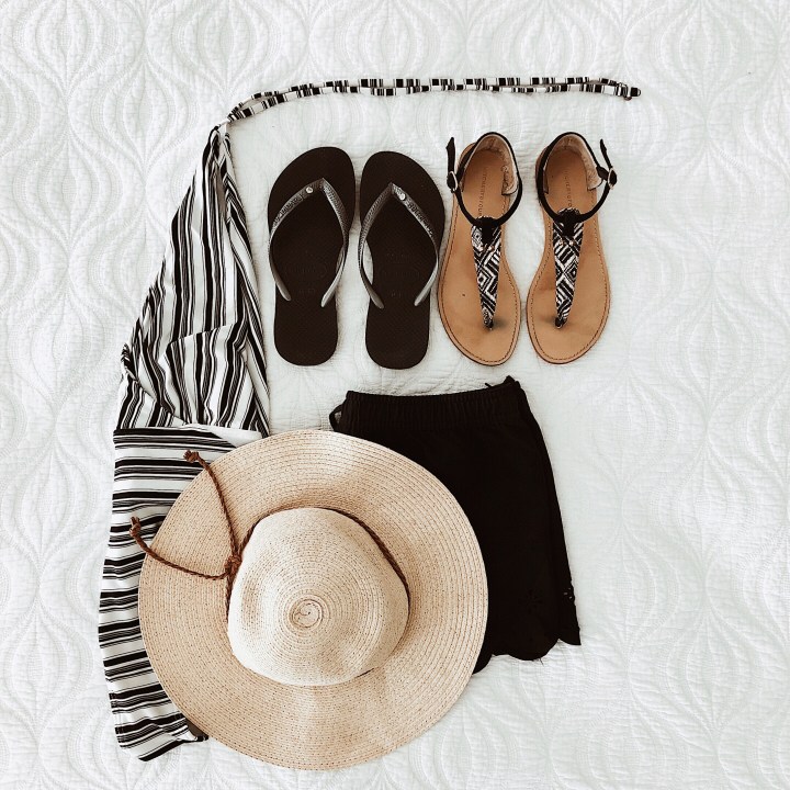 Flat lay of swimmers, sun hat, flip flops, sandals and swim shorts.