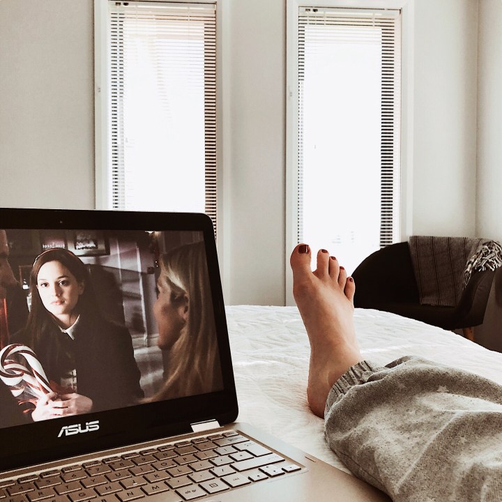 Woman laying on bed watching Netflix.