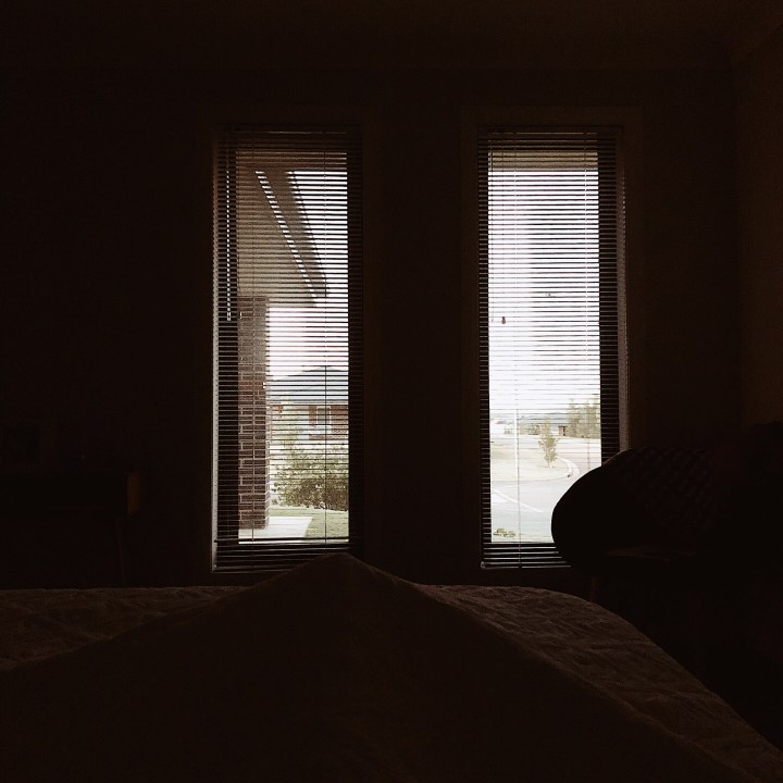 Looking out to the bright light from a darkened bedroom.