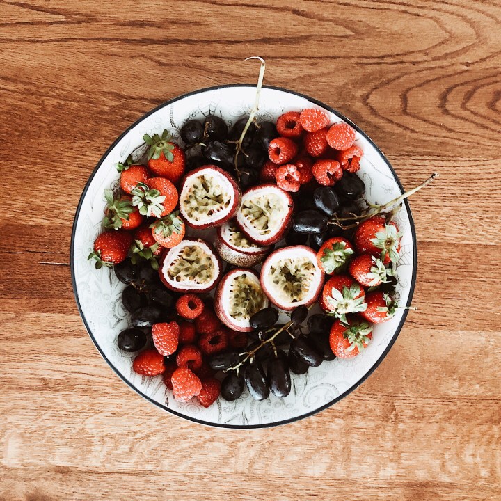 Bowl of passionfruit, grapes, strawberries and raspberries.