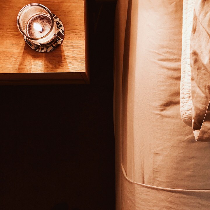 Candle on beside table, beside bed.