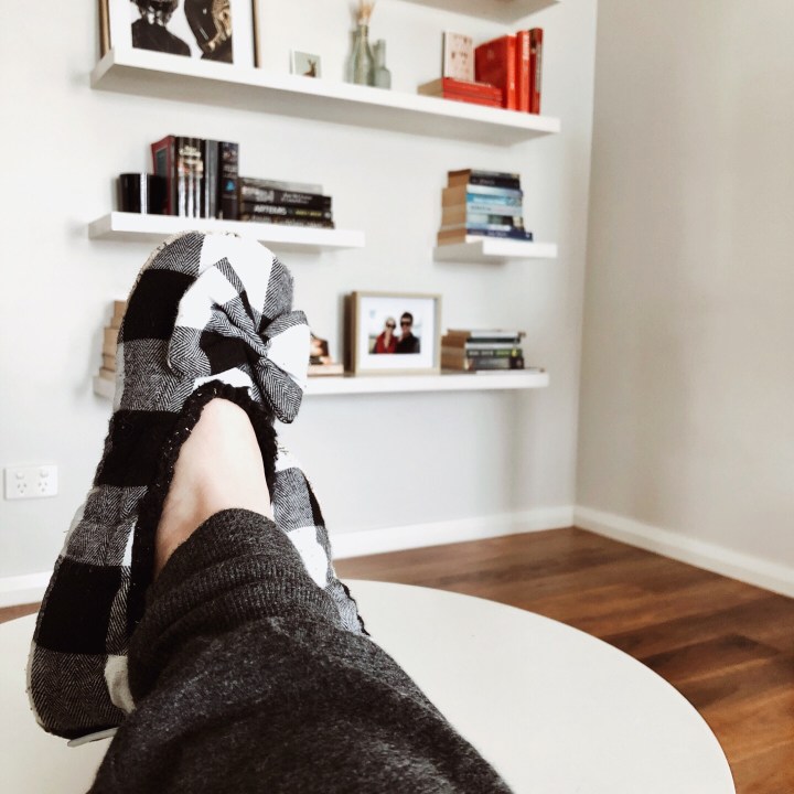 Feet in slippers on stool in lounge room.