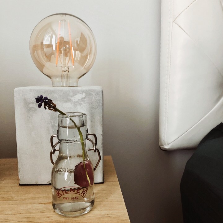Muscari flower in jar on bedside table.