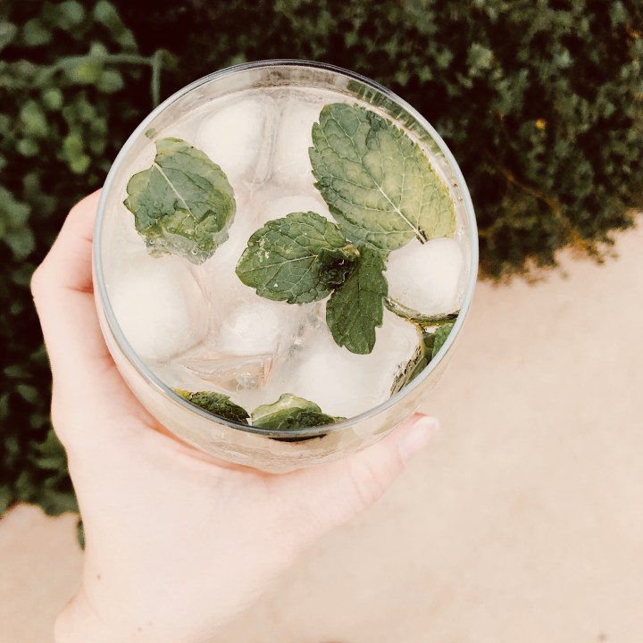 Hand holding glass of elderflower spritz.