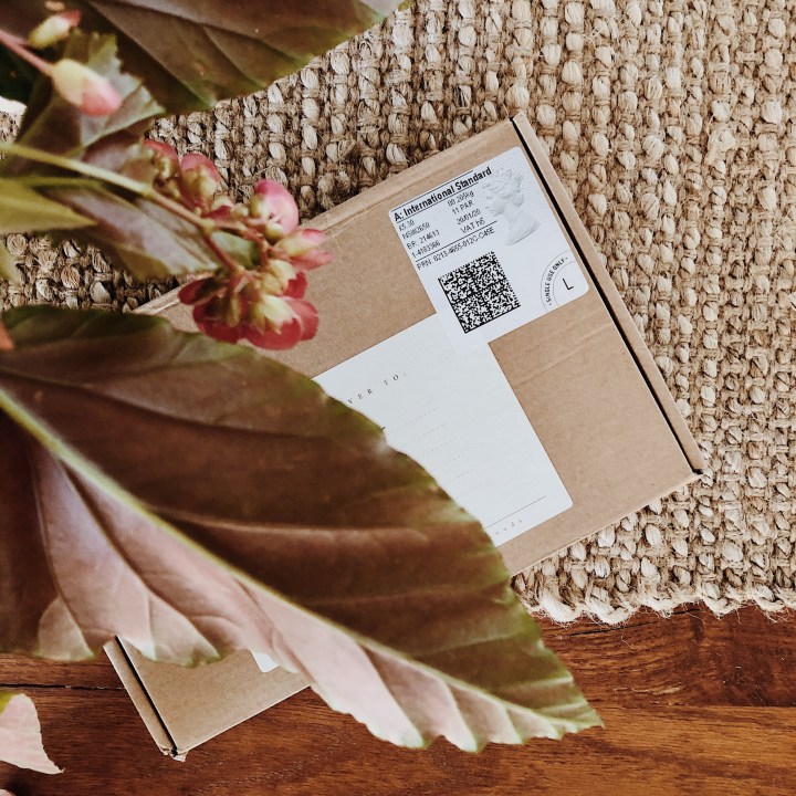 Package underneath vase of greenery.