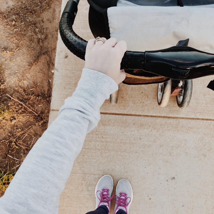 Looking down on a woman in active wear pushing a pram.
