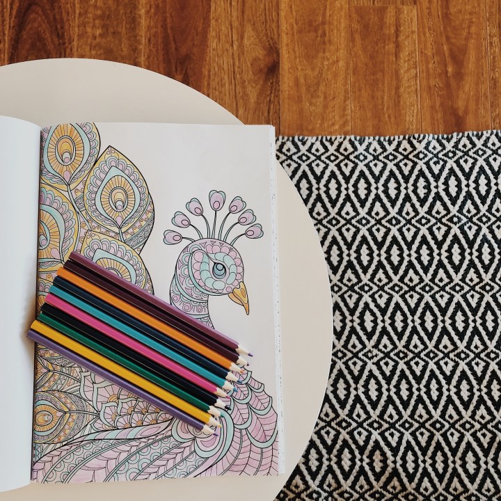 Looking down on a colouring book and pencils.