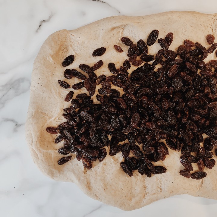 Hot cross bun dough scattered with muscat soaked sultanas.