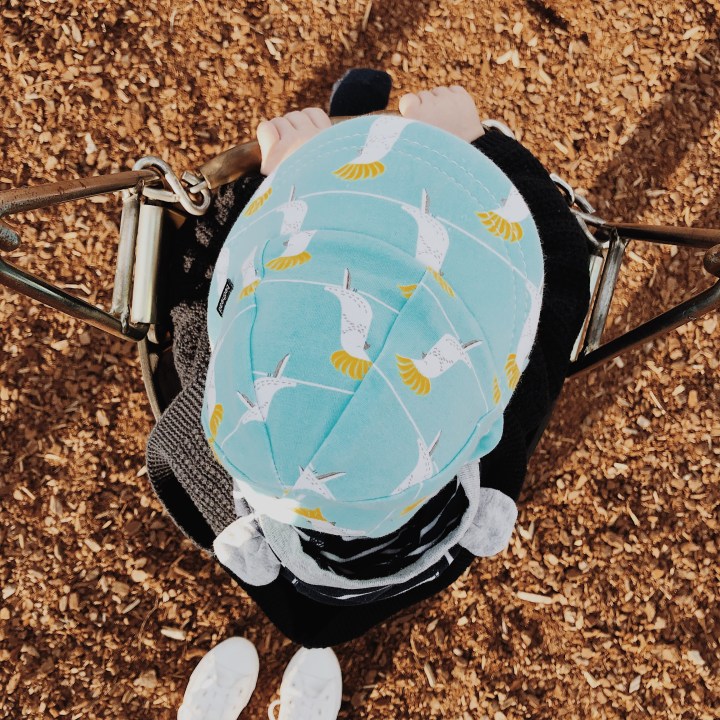 Looking down on a little boy sitting in a baby swing.