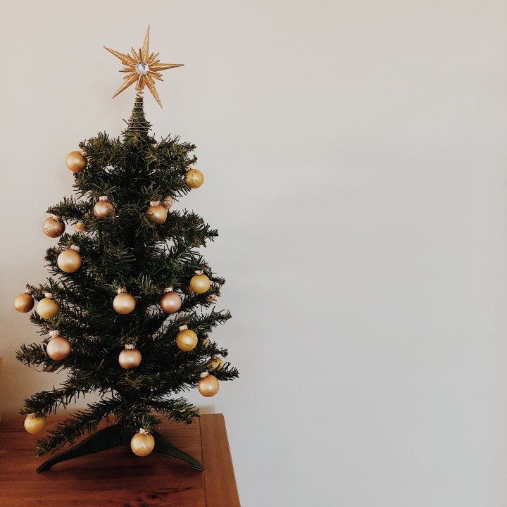 A small Christmas tree decorated with gold and bronze baubles and topped with a gold star.