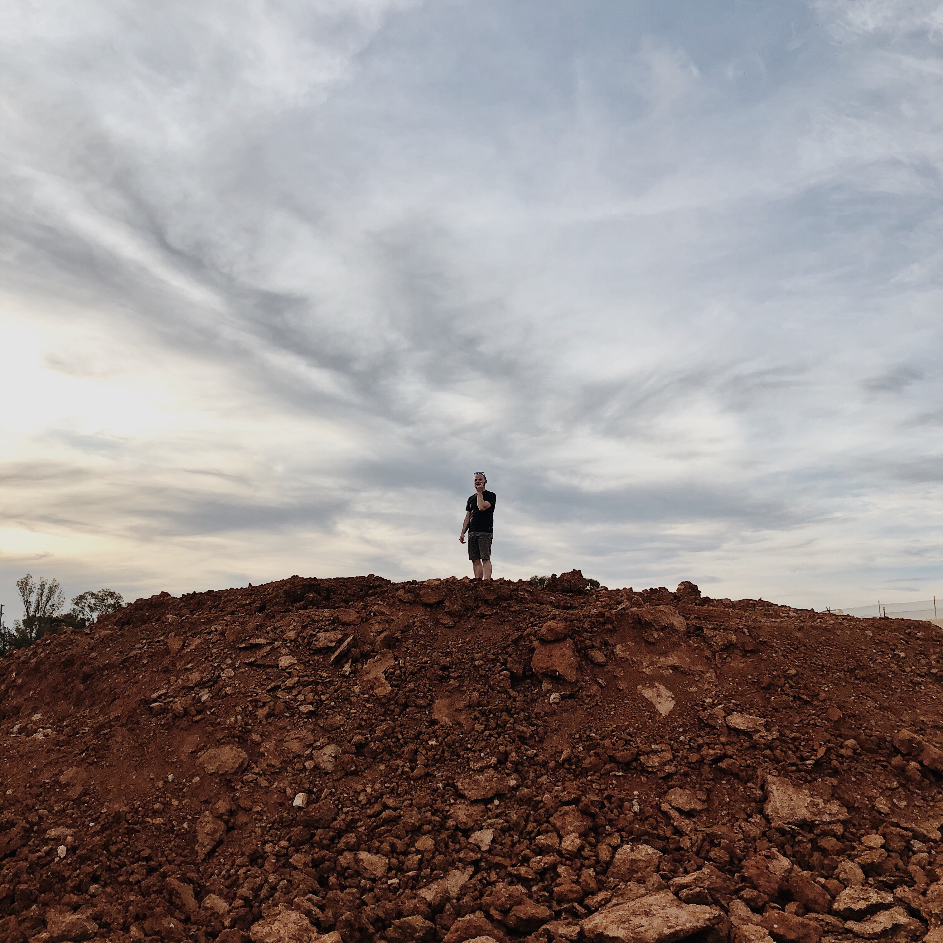 Man standing atop of a pile of dirt.