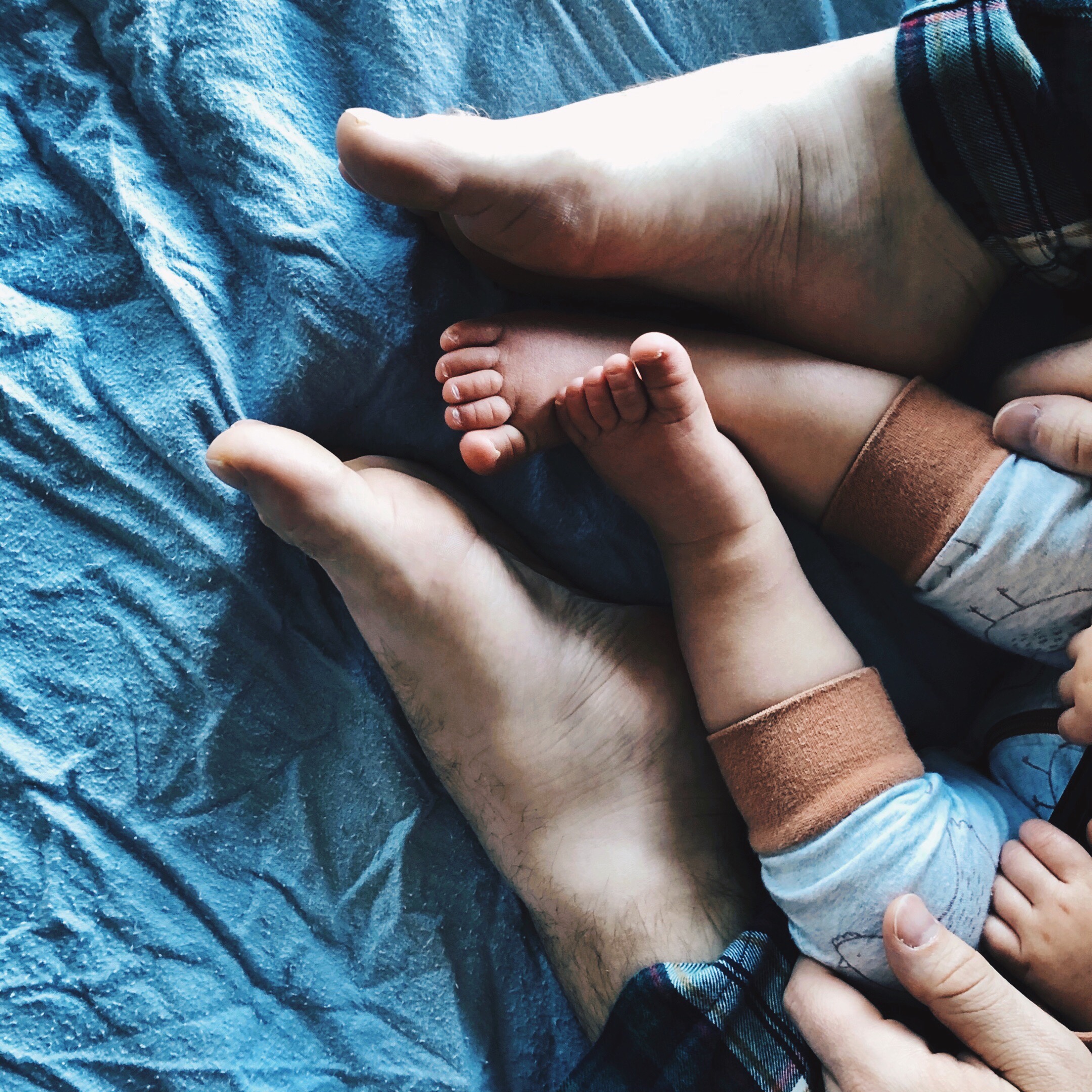 Toddler in pyjamas sits between a father's legs, also covered in pyjamas.