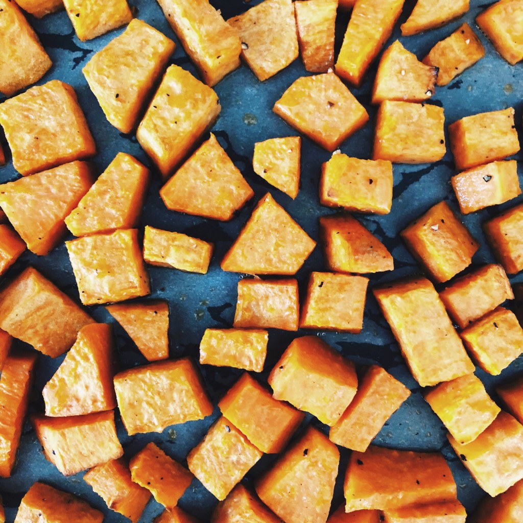 Roasted cubes of sweet potato on a baking tray.