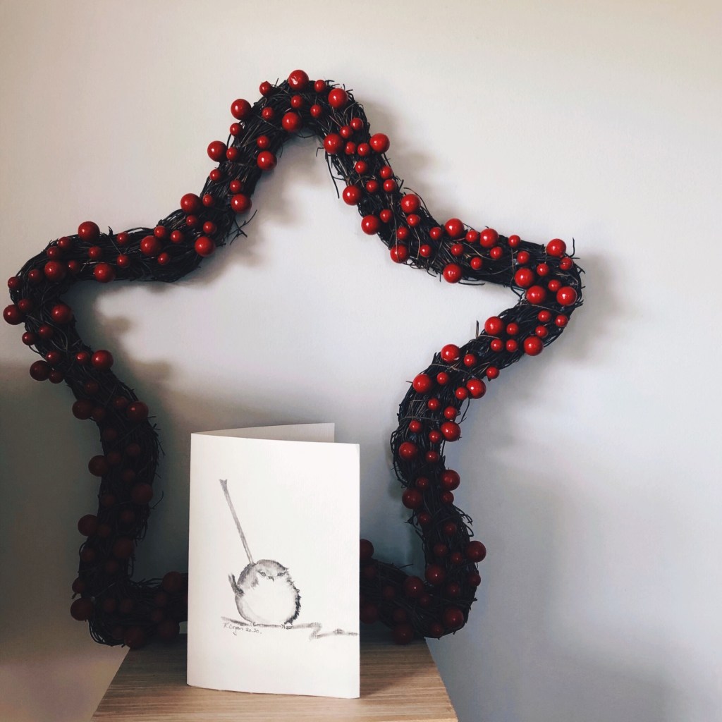 Star shaped Christmas wreath with red berries near a hand drawn picture of a bird.