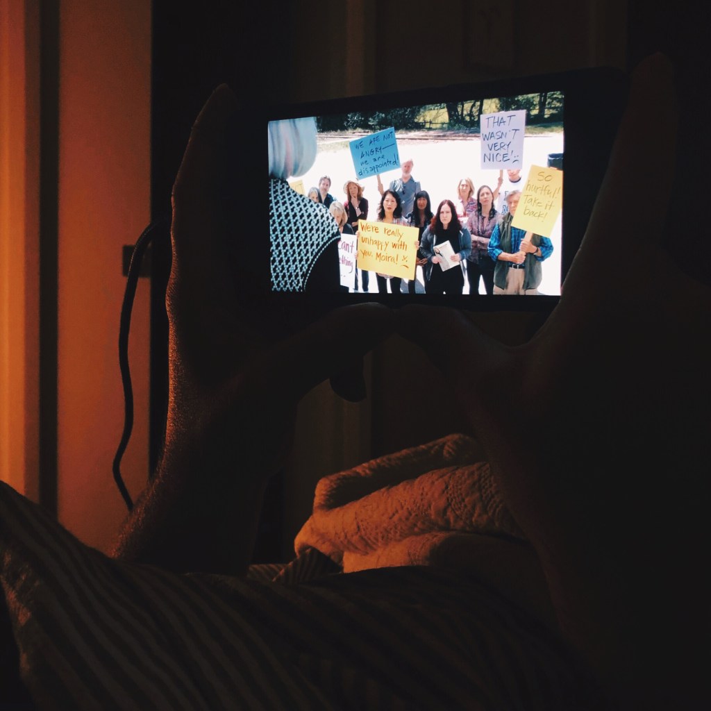 Phone playing Schitt's Creek in a lamp-lit room.