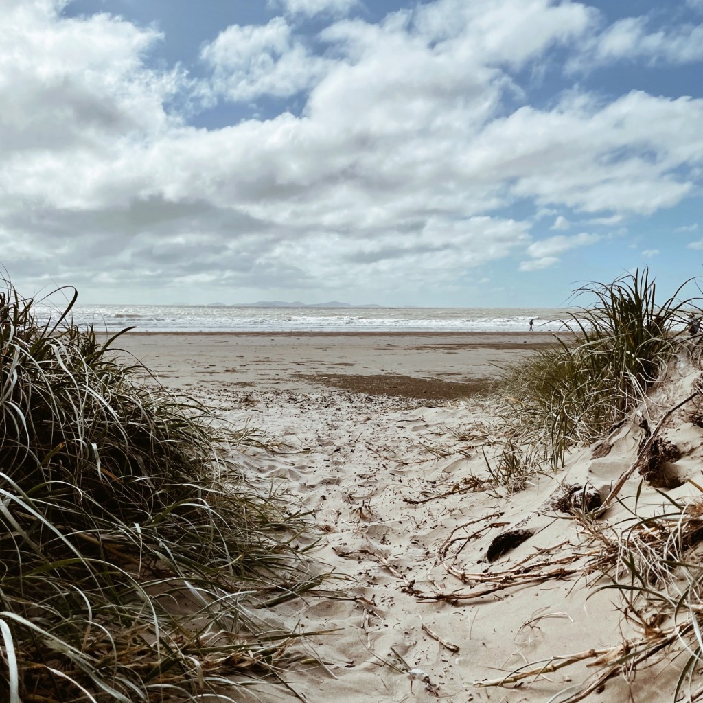 Looking through grassy sand dunes to Farnborough Beach, Yeppoon, Queensland, Australia.