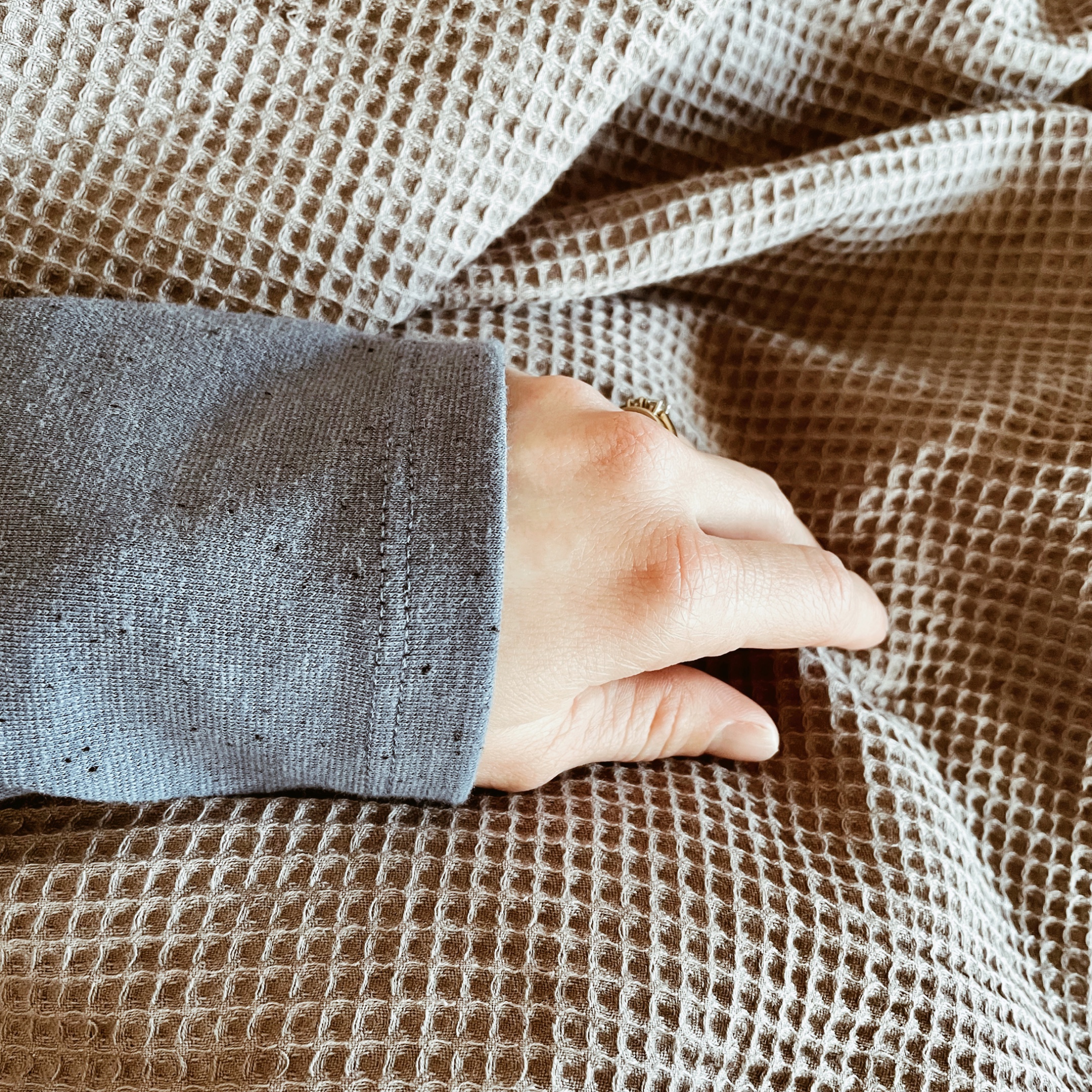 Woman's arm on top of a grey waffle duvet cover.