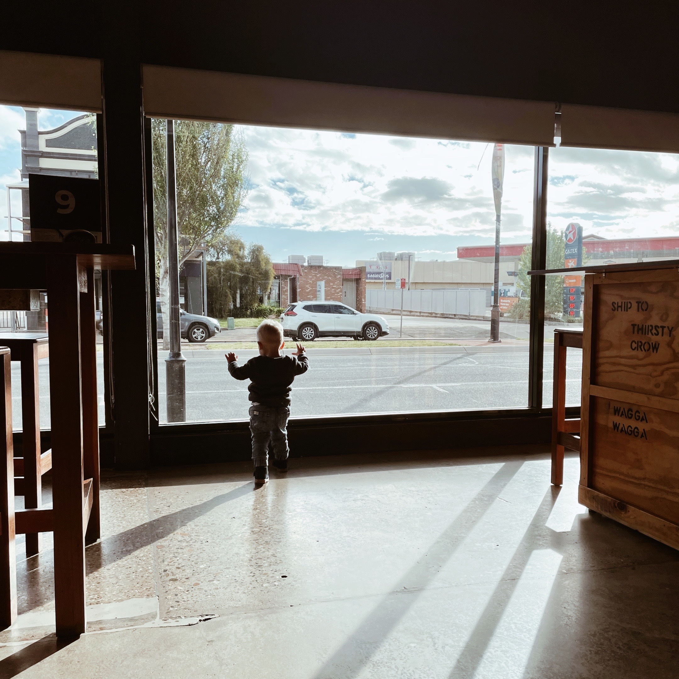 Toddler looking out of a window onto the street.