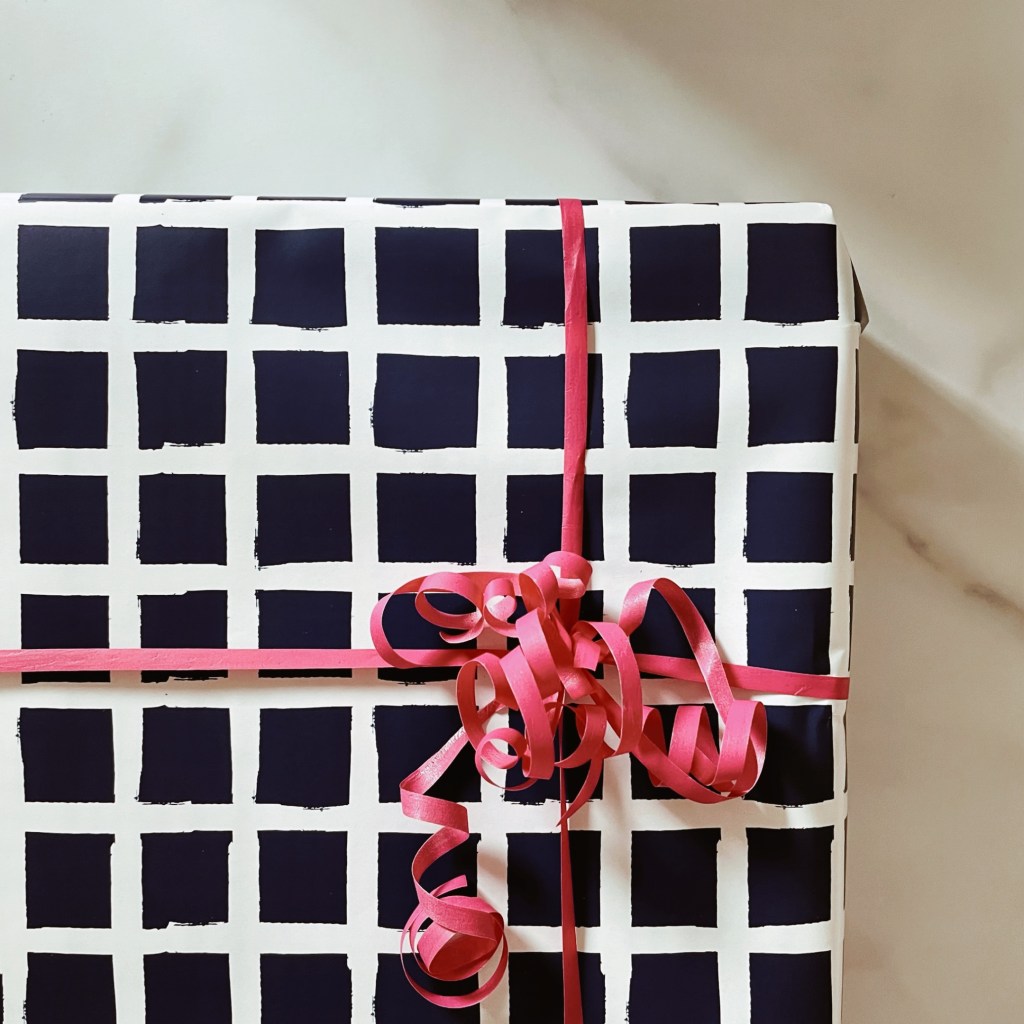 Present wrapped in blue and white paper with bright pink ribbon.