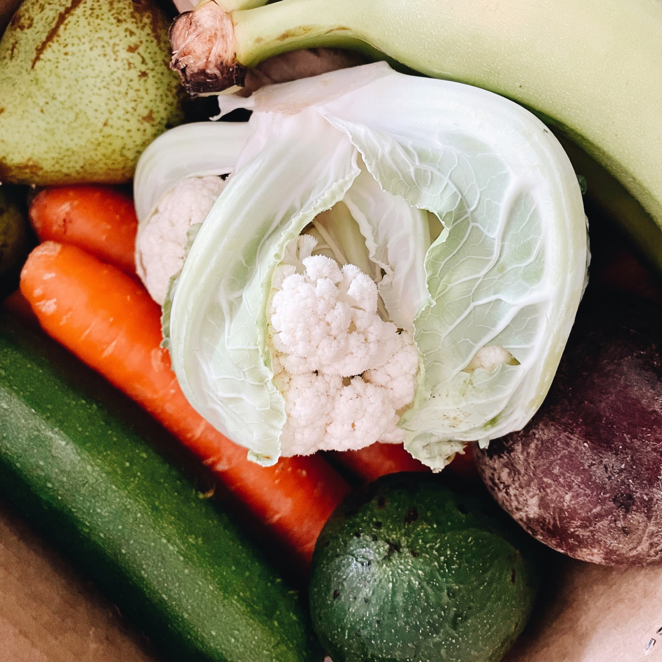 A variety of fruit and vegetables in a cardboard box.