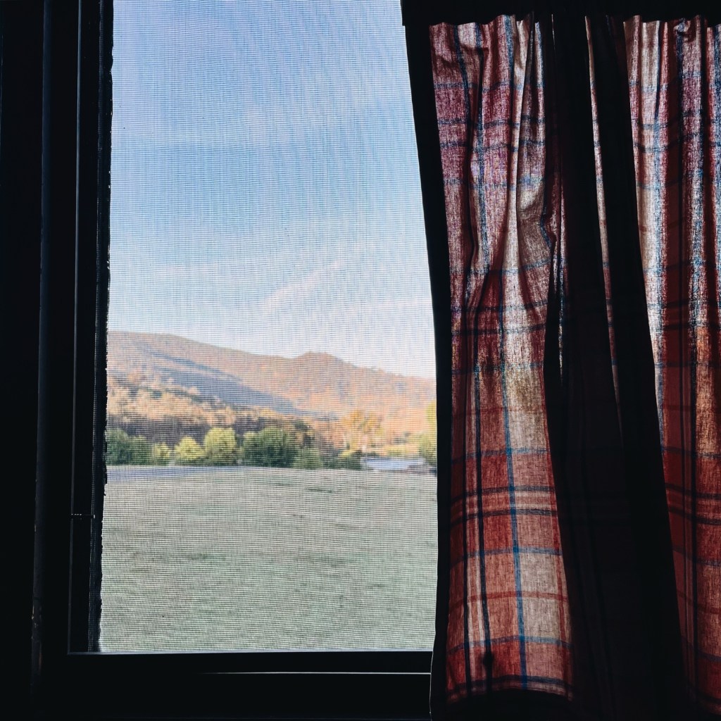 Looking through a red checked curtain to undulating countryside in Victoria, Australia.