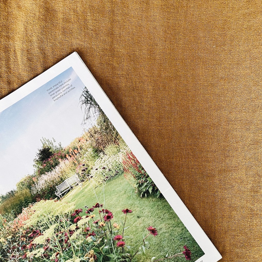 Open magazine showing a grassed path surrounding by full flower beds.